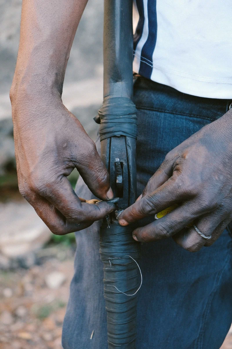 Close-up of weathered hands repairing a taped handle