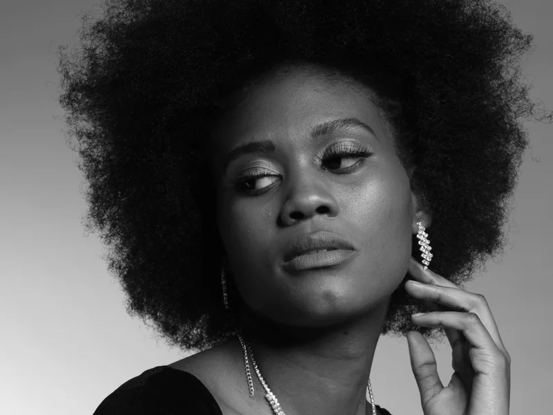 Black-and-white studio portrait of a woman with an afro and crystal earrings