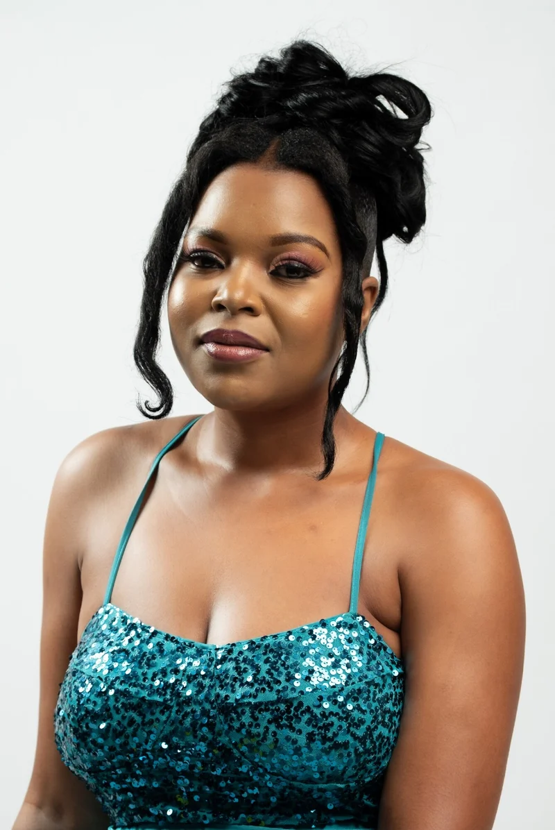 Studio portrait of a woman in a teal sequinned dress with her hair in an updo