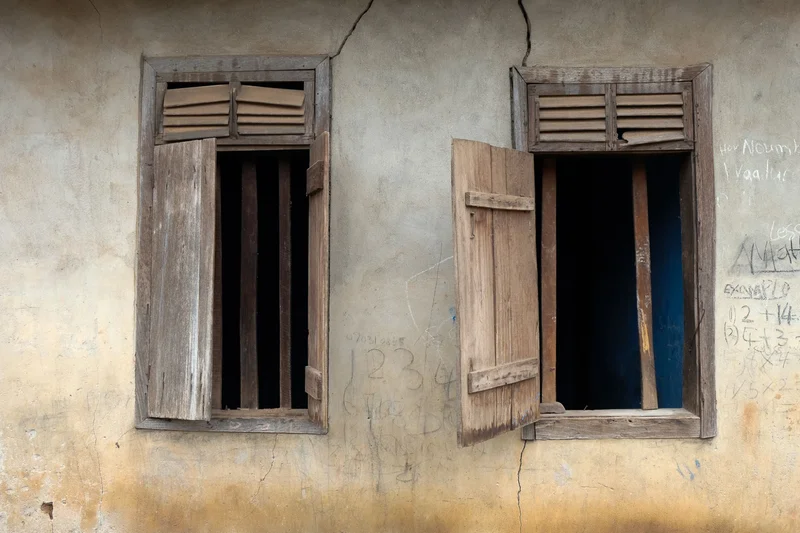 Two open-shuttered windows with chalk numbers and lessons on the plaster