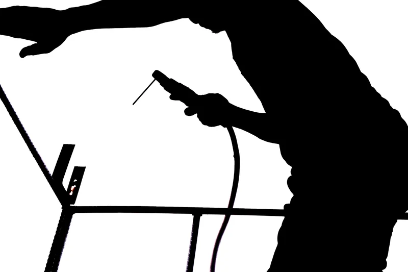 High-contrast silhouette of a welder at work on a steel frame