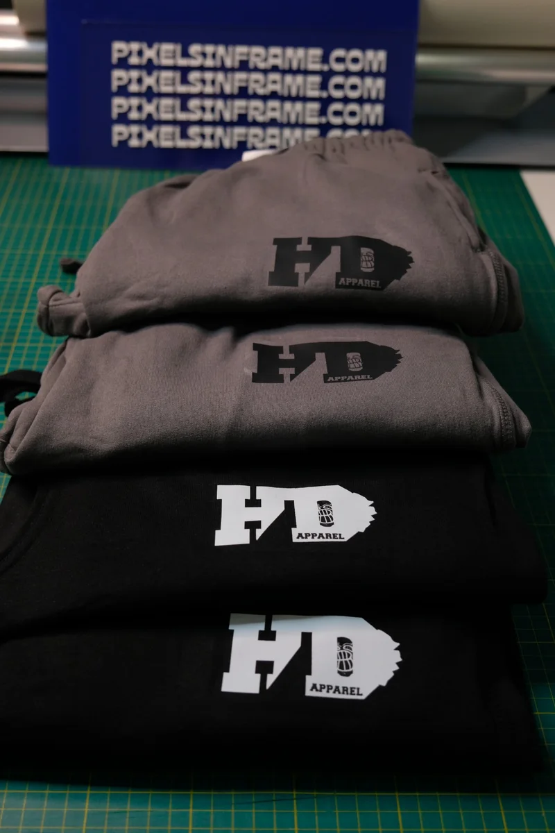 Stack of grey and black HD Apparel garments printed with the HD logo