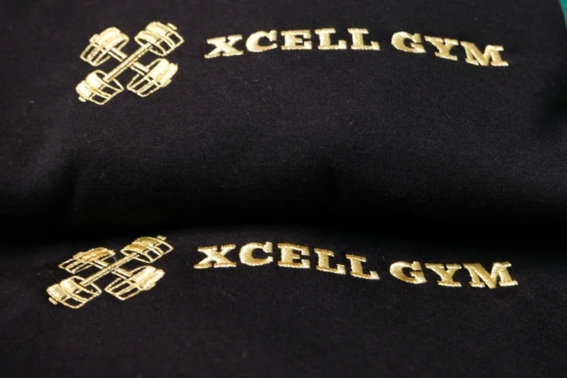 Gold Xcell Gym logo embroidered on black garments