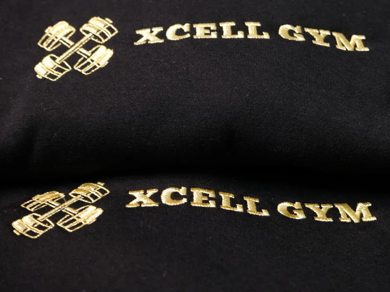 Gold Xcell Gym logo embroidered on black garments